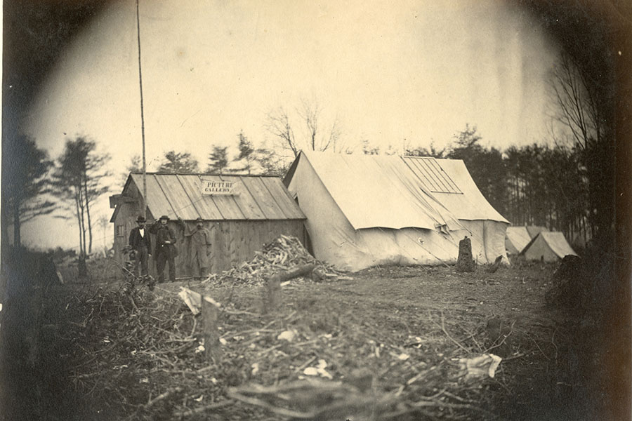 a black and white photo of the photographers home. half of it is a tent and the other half is a wooden building