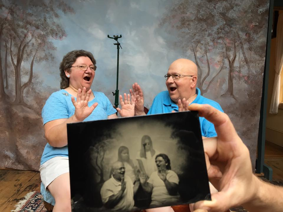 A couple pose in the studio looking frightened, in the foreground their tintype shows two young girls standing behind them... that aren't in the live image... spooky! Striking your tintypes can be fun!