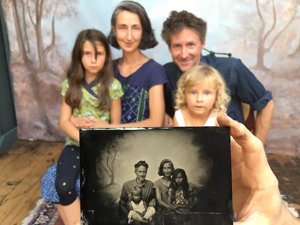 A photogenic family (husband, wife, 2 kids) huddle together for their tintypes, featured in the foreground.